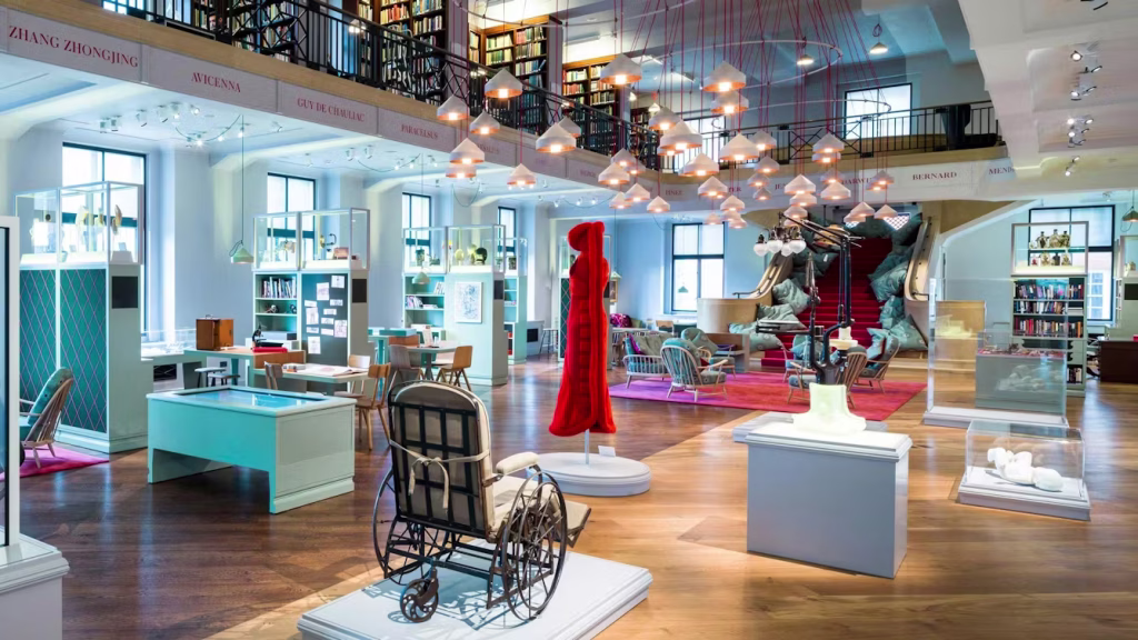 A room with objects in display cases, desks and chairs.